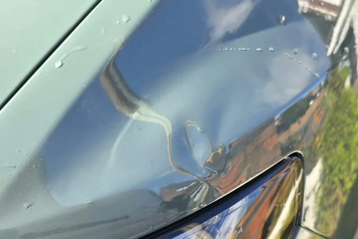 Small dent near the headlight on a car bonnet
