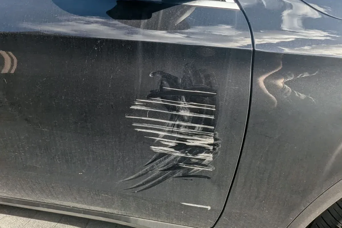 Long scratches in the paint of a dark car door